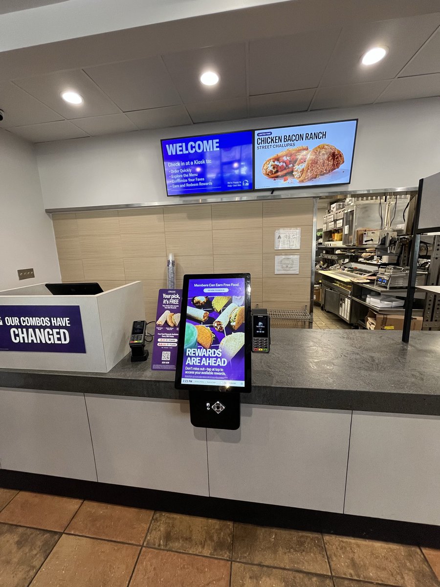 MykkiBlanco's tweet photo. Everything in America is a weird Amazon shell now. This is what’s left of the interior of a Taco Bell, a framed painting denoting a more festive past inside a grayscale soulless box. DAMN https://t.co/yWqCH7lDs5