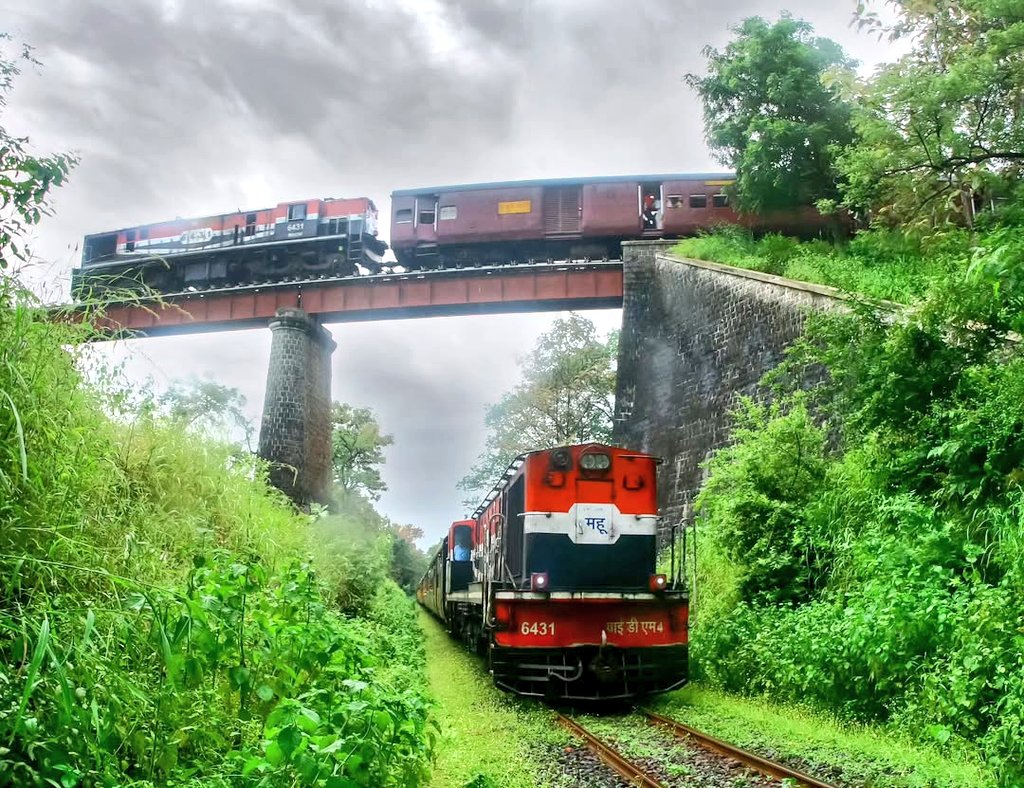 Ananth_IRAS's tweet photo. The beautiful capture from 2015 of the famous Dhulghat spiral with two MG trains passing above a below the viaduct - now a defunct station on the Akola-Khandwa section, in the jurisdiction of @drmned in @SCRailwayIndia! Pic courtesy, @sidelower!

The Dhulghat Spiral, historically known as "Char ka Ankda" (digit of four), was a renowned engineering marvel on the Akola-Khandwa meter gauge line in Maharashtra's Melghat Tiger Reserve. It featured a 193-metre-long steel viaduct allowing trains to circle a hill, overcoming steep gradient changes before the line was closed for gauge conversion in 2017.

The track formed a, roughly "4" shape in the Devnagari script (char ka ankda - "४")  to manage a steep descent across a shallow valley. The spiral was a highlight of the Akola-Khandwa meter gauge section, which once served as part of a major, scenic, north-south rail route. #IndianRailways #photography @godbole_shilpa @docbhooshan @Mohansinha