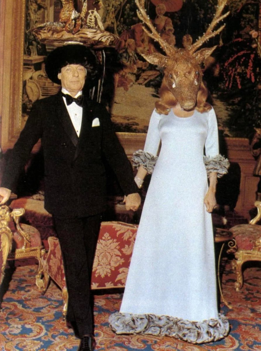 redhistoria's tweet photo. En 1972, Marie-Hélène de Rothschild organizó el Baile Surrealista en el Château de Ferrières, cerca de París, una de las fiestas de la alta sociedad más misteriosas del siglo.

El Baile Surrealista de 1972 sigue siendo una de las reuniones más comentadas de la aristocracia del siglo XX.

Presentado por Marie-Hélène de Rothschild, destacada socialité y mecenas de las artes, el evento tuvo lugar en el opulento Château de Ferrières, antaño una de las residencias privadas más imponentes de Francia. La temática era el surrealismo, inspirado en las obras de Salvador Dalí y otras figuras de la vanguardia. Los invitados debían llevar trajes elaborados y a menudo inquietantes que difuminaban la línea entre el sueño y la realidad.

Los Rothschild, largamente vinculados a las finanzas y la filantropía, demostraron aquí su influencia en los círculos culturales, reuniendo a artistas, aristócratas y figuras políticas en un ambiente que era a partes iguales teatro y mascarada. Las fotografías del baile muestran máscaras de animales, moda distorsionada y una decoración onírica, convirtiéndolo en una representación visual del surrealismo mismo.

Entre los invitados se encontraba Salvador Dalí, quien diseñó varios de los detalles más extravagantes de la velada, consolidando aún más el vínculo entre el arte surrealista y el espectáculo de la alta sociedad.