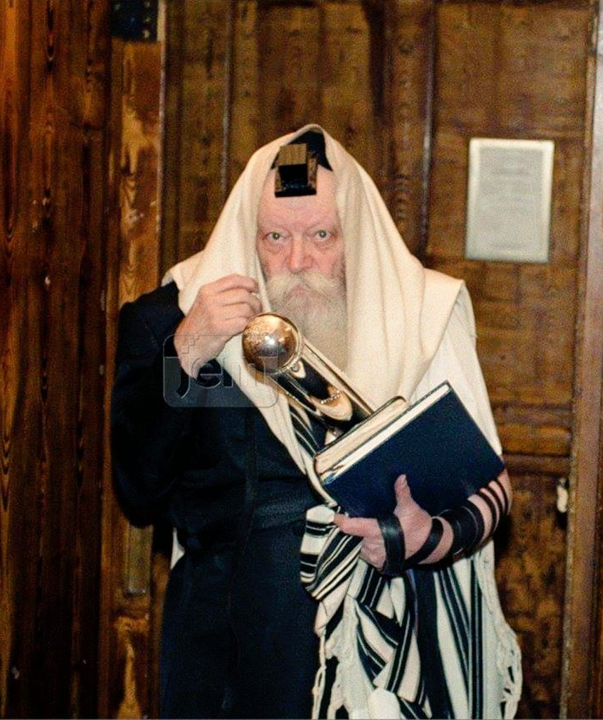 "בִּרְאוֹתָם יַחַד תְּכֵלֶת מָרְדְּכַי"
הרבי יוצא מתפילת שחרית כשהוא עטור בטלית ותפילין ומגילת אסתר בידו, פורים תש"נ (1990)