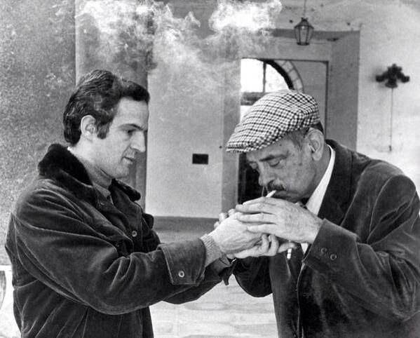 François Truffaut giving Luis Buñuel a light for his cigarette.