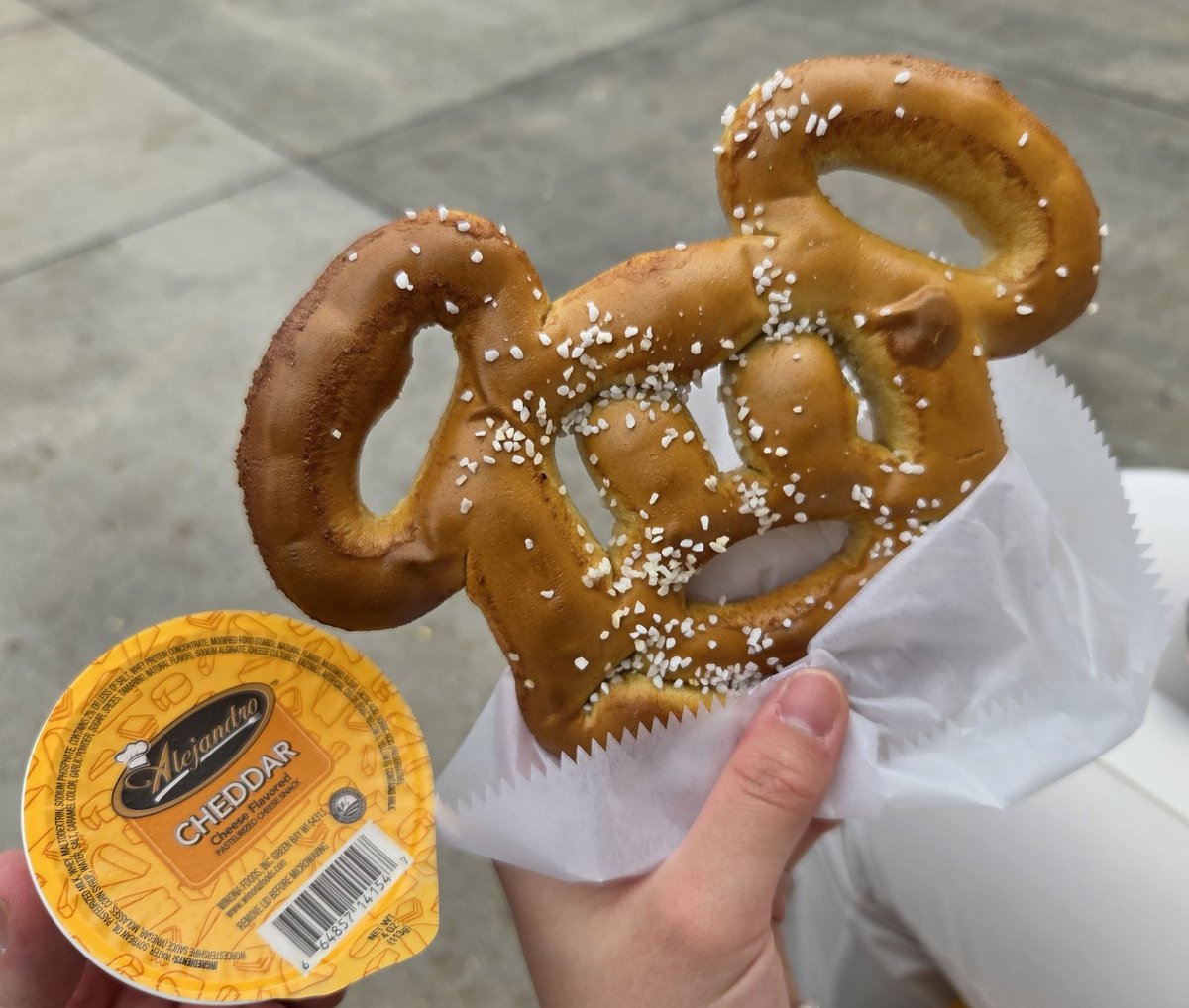 Wells_1983's tweet photo. フロリダディズニー行く人にめちゃくちゃ注意して欲しいのがこのミッキー型のプレッツェル。

この付いてる白い塊、全　部　塩　。
あまりにもしょっぱい、というか塩辛いまである…

おまけに付いてくるチーズソースも大量だし、チーズというよりしょっぱいソースなので更に苦しみを増大させる罠… https://t.co/dz41zkUIyM