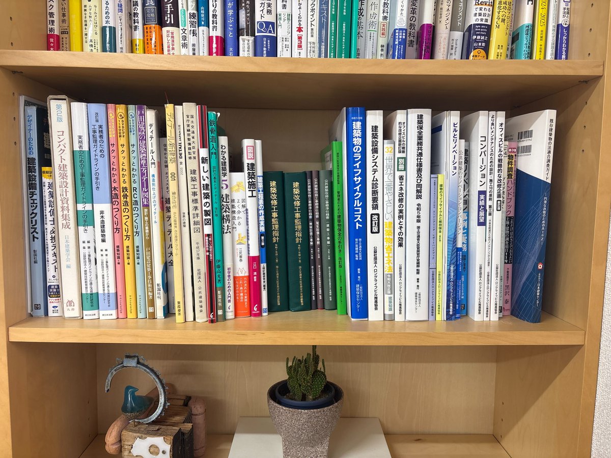 yu_sakuma's tweet photo. 弊社では改修のための初期調査や、改修設計に欠かせない専門書を約50冊揃え、いつでも手に取れるよう打合せデスクの隣に備え付けています。

実はこれらの本は事務所で閲覧用ともう1セット「予備」を用意しています。社員が担当しているプロジェクトに関連の深い本は、予備から自由に持ち出し可能で、現場や自宅でも必要な時にすぐ深い知識にアクセスできる体制を整えています。
さらに、写真が豊富でDVDが付属している『実務者のための工事監理ガイドライン』や、各構造の『サクッと分かる〇〇造のつくり方』シリーズなどは、会社から「一人一冊ずつ」全員に配布しています。自分専用の資料としていつでも参照できるようにしています。

これらはすべて、「スキルマップ」と連動しています。STEP1からSTEP3へと着実に成長するための「処方箋」として、どの資料を読み込むべきかが明確に定義されています。
「どうすれば実務と座学を両立できるか」を考え、まずは必要な資料を会社として集めるところから始め、今の形に落ち着きました。

建築再構企画の教育体制について、より詳しく知りたい方は固定ページのリンクからYouTube動画もぜひご覧ください！