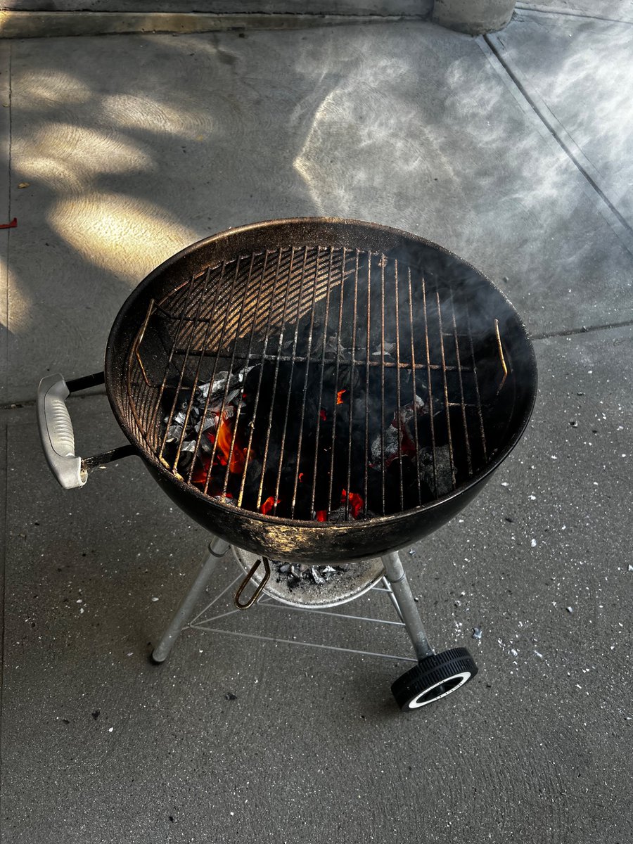 I am cooking, outside, on a grill. It is a beautiful day.