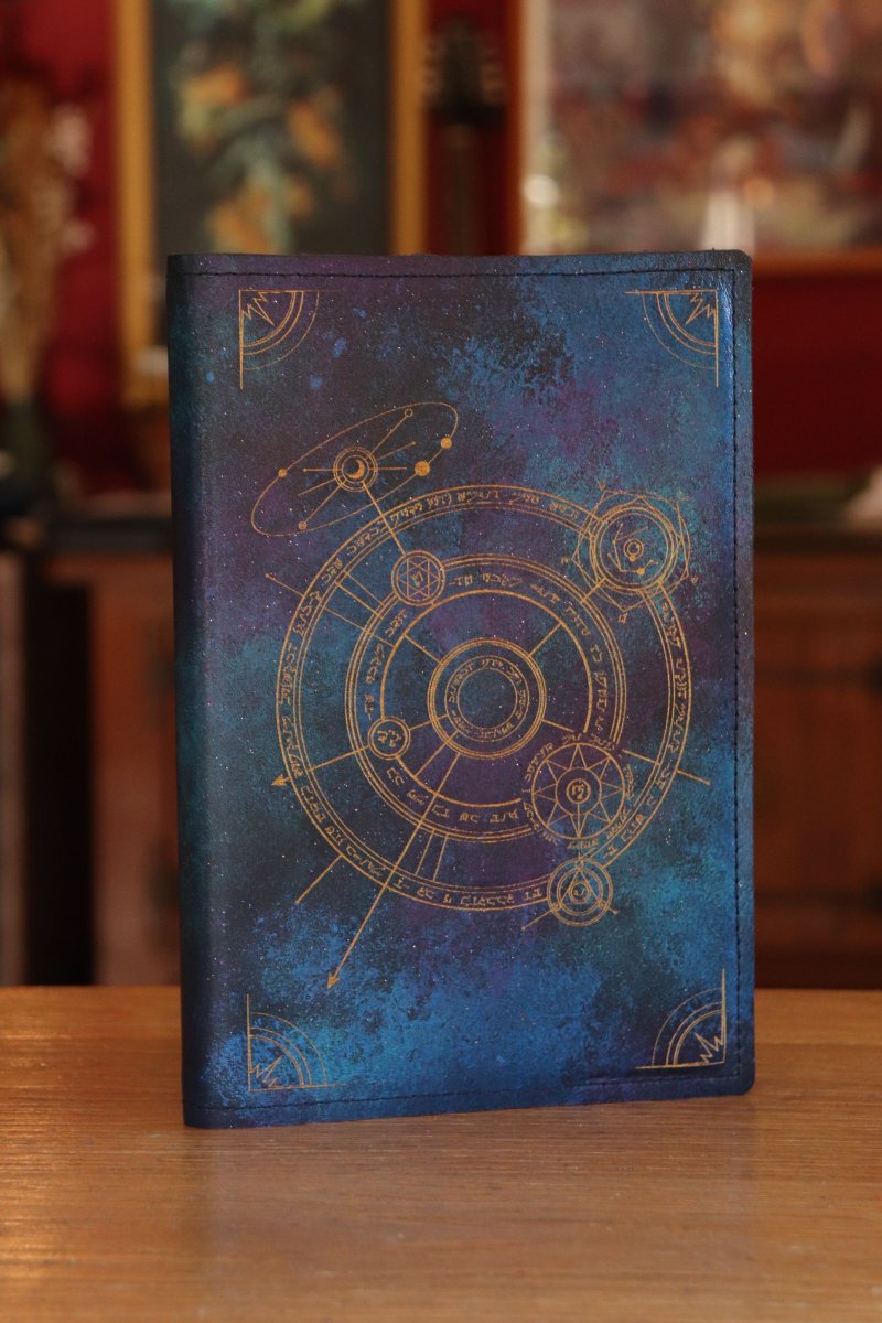 SpeechlessBard's tweet image. All done! A sparkling Galaxy leather A5 notebook, with our Conjurer Circle engraving and gold inlay. The leather is a sleeve, so you can swap out the notebook when it's full 📚️ 
You can find more notebook sleeves in our shop! ⭐️ 
#ttrpg #notebook