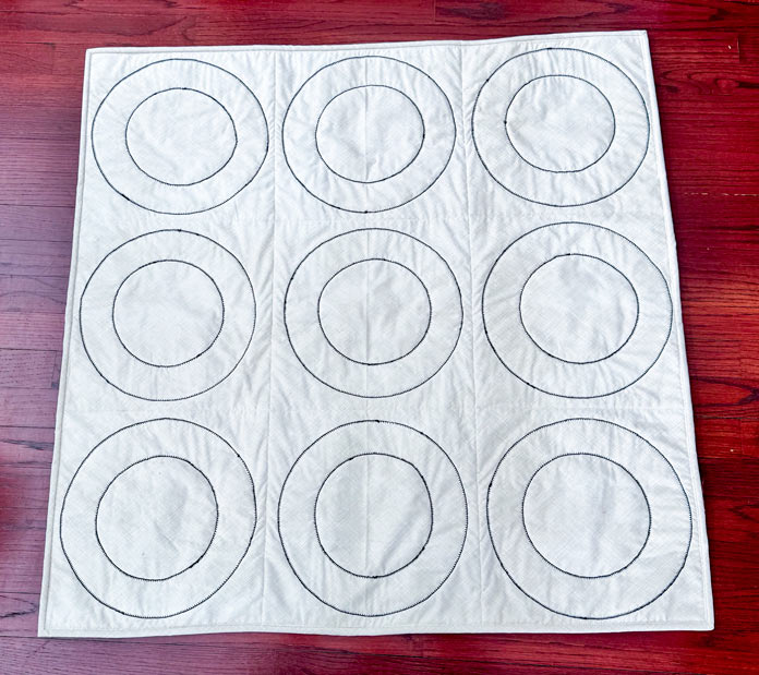 QUILTsocial's tweet photo. Final step and it is a fun one. Paul bastes fast with Odif 505, quilts with a double blanket stitch that also secures the rings, then binds it up and shares game ideas for tic tac toe and a toss game. https://t.co/LH4GUhk2gd #Odif505 #QuiltTutorial #QuiltBasting https://t.co/mLuXqkNOlO