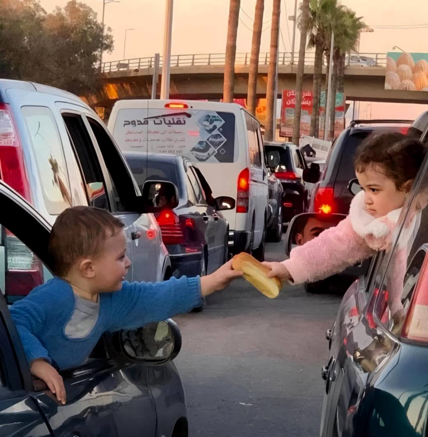 opfascism's tweet image. This gesture of humanity between two children was captured as their families wait in traffic to escape the bombing in Lebanon.

They're leaving everything behind not certain what will be left when they return.

#NoWar #Anonymous