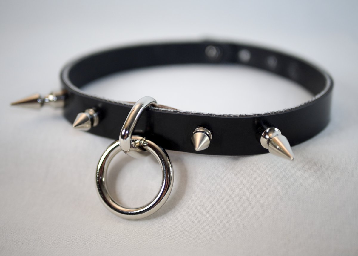HELDgear's tweet photo. The Sydney Choker is now available at the home shop and Etsy. It's an affordable but powerful black choker featuring 25mm, and 12mm conical brass and nickel spikes, plus a loop and ring for play time. It is adjustible, latching together with a stud and notches. https://t.co/39fydllgLK