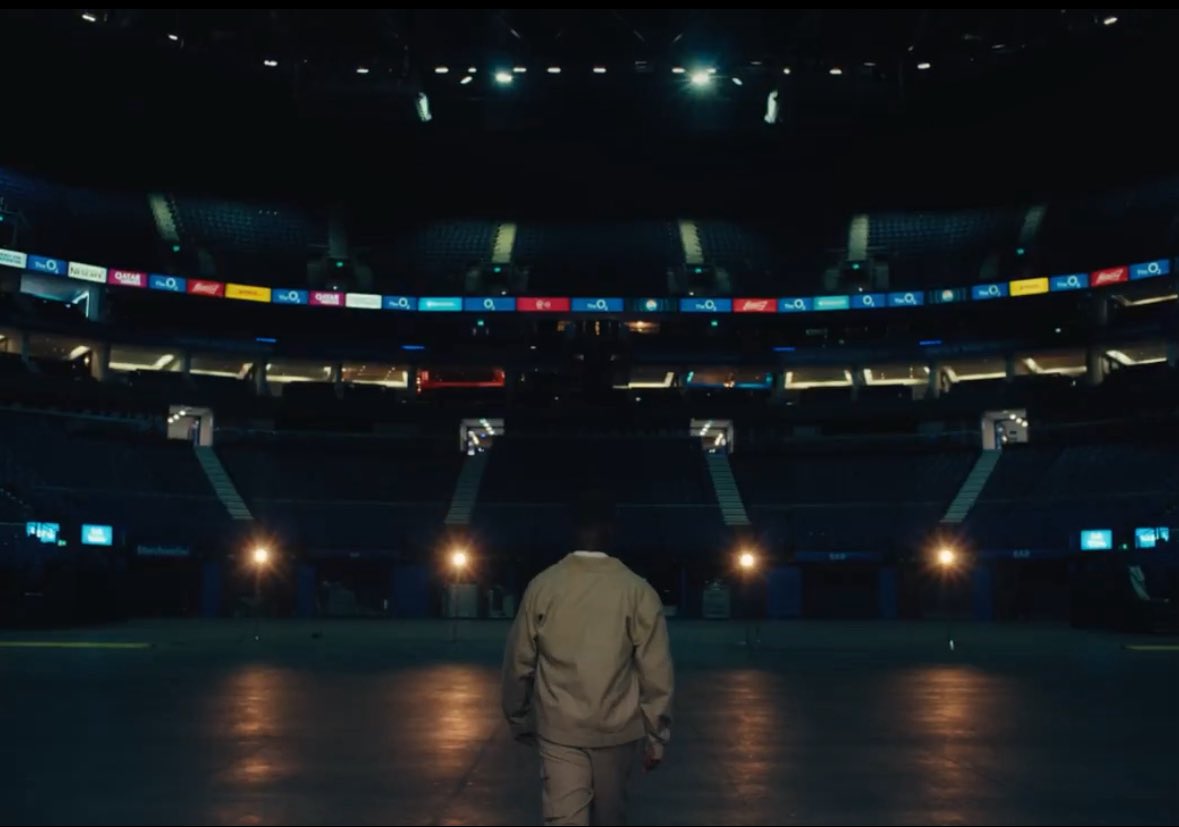thejosephmireku's tweet photo. Well, since you asked, here we go:

The scene opens with an “a capella” rendition of lyrics referencing his goal of selling out the O2. This seems normal. But if you look closely, you see he’s set against a red backdrop, which is strange because for filming and production, you would normally expect a greenscreen. Straightaway we see the “eye-red”, the sweat, the blood, and the suffering creating the background with which he has gotten so far.

The red serves a hidden purpose too. The red cape is what a matador waves in front of an angry charging bull. Throughout his career, he has had these big charging bulls always attacking his progress. This is the moment where he waves the red cape. Though entertaining for his admirers and fans, it will inevitably lead to the humiliation of the charging bulls. 

The red also recalls the campaign around the Alpha album, where red was heavily used as the central visual theme, and it eventually became the colour scheme for that year’s Rapperholic concert in 2019 (7th edition. We will come to this later).

Moving on, the camera pans out and we see a clapperboard showing 777. Sarkodie likes to rap about his hustle, but which song is his most personal and powerful exploration of his suffering? Mile 7 Freestyle. The show will also take place in 2027, on the occasion of Ghana’s 70th Independence Anniversary. You might think it’s 7 not 70 so this is stretching it, but..Sarkodie was born on 10 July, i.e the 10th day of the 7th month. 10*7 gives you 70. Interestingly, the 2019 Rapperholic concert, which carried the strong red theme during the Alpha campaign, was also the 7th edition of Rapperholic.

Finally, Sark is looking at the viewer mot of the time, but just when the actual shoot starts with the clapperboard, he begins to walk away. He wants you to come with him on this journey. He wants you to be part of this historic moment.