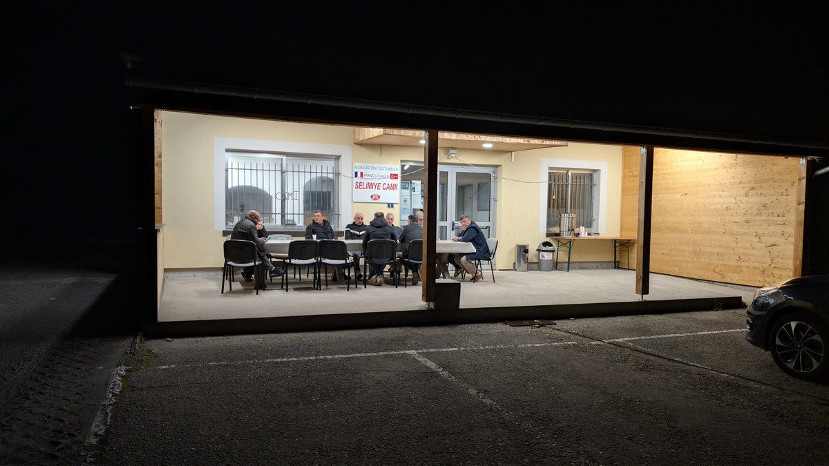 aydinomer's tweet photo. Fransa'nın tenha bir kasabasında iftardan sahura bir Ramazan akşamı.

Zaman durmuş gibi.
İçilen çaylar, kahveler.
İçeriği değişen ama tadı hiç değişmeyen sohbetler.

En son 5 yıl önce gelmiştim buraya.
Moder ırmağı ve tren yolu boyunca uzanan vadide, sırtını devasa bir ormana dayamış Ingwiller Selimiye Camii.

1970'lerde gelen ilk nesil gurbetçilerin çoğu artık yok.
Onların çocukları da bayrağı yeni nesle teslim etmişler.

Hemen yanındaki Bouxwiller'de 1976'da Giresun'dan gelip baba-oğul yıllarca çalıştıkları fabrikanın karşısında, onun 2 katı büyüklüğünde bir işletmeyi açan büyüğümüzü ziyaret ettik.

60 yılı geride bıraktığımız Fransa'ya göçün her aşamasına dair unutulmaz hikayeler dinliyor, kıymetli anılar biriktiriyorum.