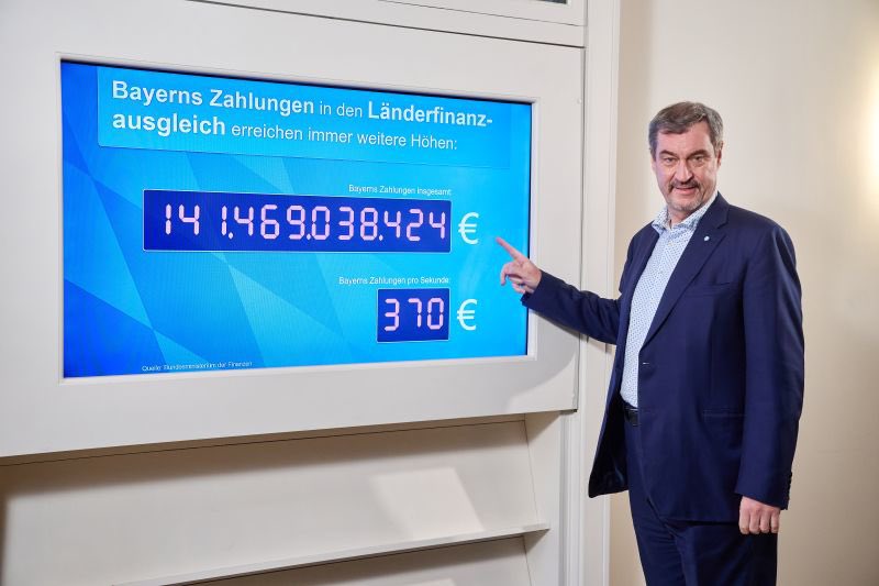 Herr Söder zeigt auf die Schuldenuhr von Jens Spahn. 
(Danke <a href="/eLHa_Schwerte/">Simon L.-H.</a>)