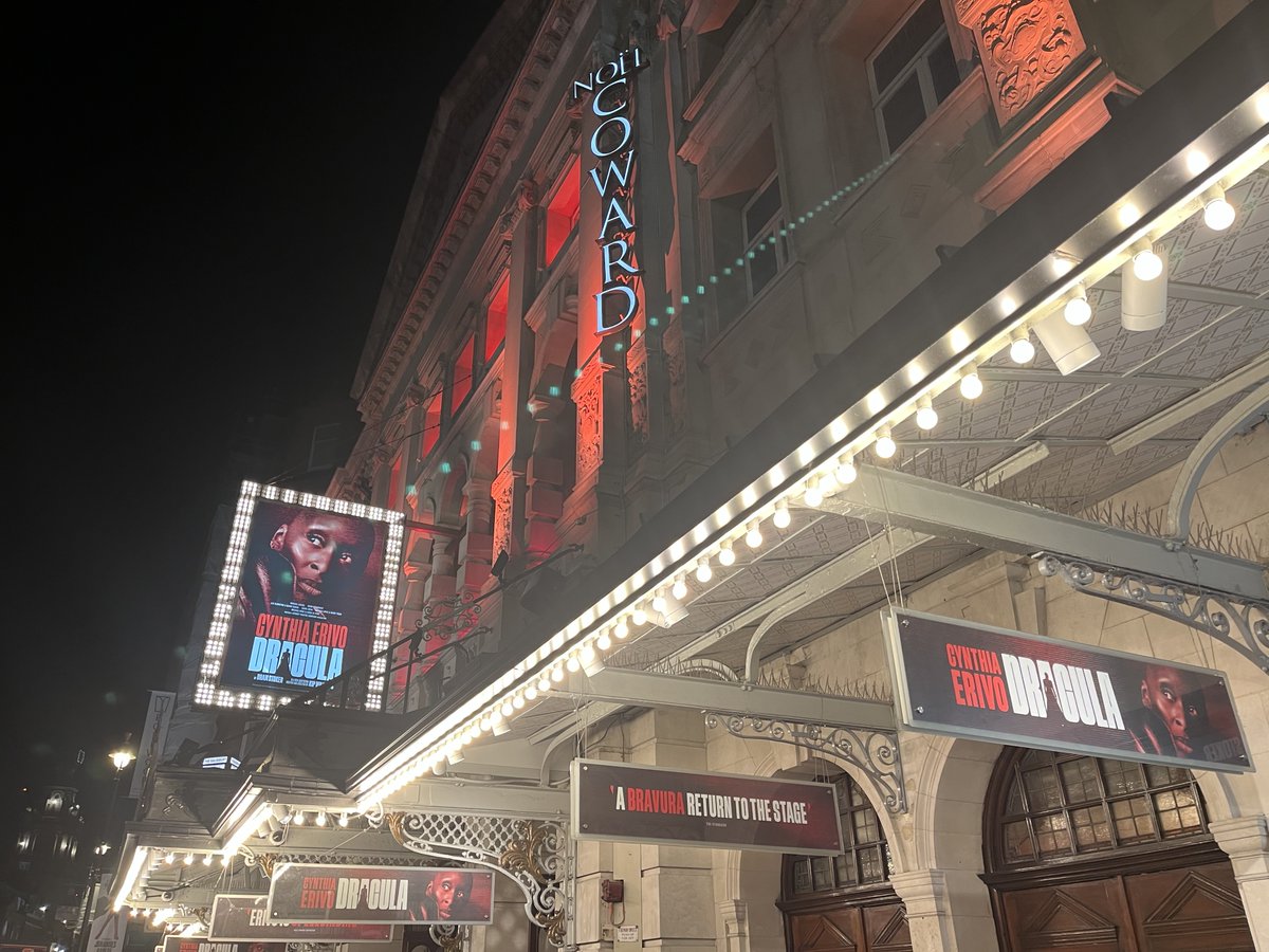 tomikawan's tweet photo. シンシア・エリヴォがドラキュラ伯爵を含む二十数人の全役柄を一人で演じる「Dracula（ドラキュラ）」@ Noël Coward Theatre。ブラム・ストーカー原作、キップ・ウィリアムズ脚色・演出。

数名のカメラマンが黒子として舞台上に上がってエリヴォを撮影し、そのライブ映像が舞台中央の大きなスクリーンに投影される。このライブ映像と、事前録画された他の役柄の映像（全員エリヴォが演じる）が合成され、画面上で作品が完成する——という趣向。こういう、生演技と映像を組み合わせる上演形式をcine-theatreというらしい。

２年前に同じ演出家が同じ趣向で手がけたサラ・スヌークの一人芝居The Picture of Dorian Grayはとてもおもしろかったですが、今回は正直微妙だったかも。エリヴォの生演技を見るより画面を見ている時間の方が長いという…。エリヴォはしばしばスクリーンの裏で演技をするのでなおさら。

あと安席の関係で舞台上のスクリーンが見づらくて、座席近くに設置された小さなサブモニタを見ながら筋を追うしかない感じだった。ウエストエンドの古い劇場で、この舞台装置だと、演出家が意図した景色が見られる席はかなり限られる気がする。

The Picture of Dorian Grayはドリアンの外見やセルフイメージに対する執着を描く話で、スヌークがスマホの自撮り映像を画面に投影したり加工ソフトで映像をいじったりすることも含めて"the picture"なので、物語の主題とシネシアター形式が一致していたと思う。本作の、各キャラの手紙や日記をエリヴォがカメラ目線でナレーションする趣向は、書簡体小説である原作を、映画でいうファウンド・フッテージものに置き換えたのだとは言えるかも。でもそれだけかも…。