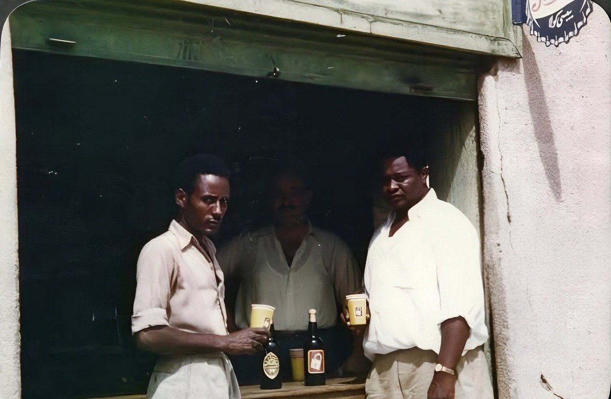 Sudanhistory280's tweet photo. قرار منع الكحول يهز الحياة الاجتماعية في السودان

29 أبريل 1984 – يواجه رئيس السودان جعفر نميري تحدياً متزايداً بعد قراره حظر المشروبات الكحولية، في بلد اعتاد فيه كثير من الناس على الشرب لسنوات طويلة. ففي جوبا ومنا��ق أخرى من جنوب السودان حيث يشكل غير المسلمين غالبية السكان، أبدى كثيرون استياءهم من إعلان نميري تطبيق الشريعة الإسلامية التي تحظر استهلاك الكحول.

وتشير التقارير إلى أن الحانات في جوبا لا تزال مفتوحة كما كانت من قبل، وأن الويسكي والبيرة والنبيذ ما زالت تتدفق خلال ساعات المساء الطويلة، خصوصاً في الليالي الحارة التي كثيراً ما تتجاوز فيها درجات الحرارة مائة درجة فهرنهايت.

أما في الخرطوم، في الشمال حيث يشكل المسلمون غالبية السكان، فيتعامل الناس مع الوضع بحذر أكبر، لكن كثيرين يقضون جزءاً كبيراً من ساعات الصباح في التفكير في كيفية الحصول على مشروب مع حلول ال��يل.

وفي جنوب البلاد ساهم إعلان نميري تطبيق الشريعة في سبتمبر الماضي في توسيع التأييد لحركة تمرد مسلحة تسعى إلى الإطاحة به، كما أن عجز الحكومة عن فرض الحظر يشير إلى تراجع سيطرتها في تلك المناطق.

ويرى بعض الدبلوماسيين أن قرار نميري جاء بدافع ديني. ويقال إن الرئيس، البالغ من العمر 54 عاماً، أصبح أكثر تديناً في السنوات الأخيرة متأثراً ببعض رجال الدين. 

وقد توقف نميري عن شرب الكحول قبل عدة سنوات، رغم أنه كان معروفاً في السابق بإقباله على الويسكي، وهو أمر كان شائعاً بين السودانيين مسلمين وغير مسلمين.

وكان من أول الإجراءات التي اتخذها بعد إعلان الشريعة توجهه إلى فندق جراند الحكومي في الخرطوم، قرب ملتقى النيلين الأبيض والأزرق، حيث قام بتكسير زجاجات الويسكي وسكب علب البيرة في النهر في مشهد علني. وبعد انتهاء ذلك العرض، انتشرت الشرطة والجنود في أنحاء الخرطوم لمصادرة المشروبات الكحولية من الفنادق والحانات والمطاعم.

وكان من المعتاد أن يجتمع الرجال السودانيون في المنازل مساءً، فيبدؤون بشرب الويسكي والبيرة ويواصلون حتى وقت متأخر من الليل، ثم تقدم نساء المنزل وجبة عشاء متأخرة، وبعدها يغادر الضيوف إلى منازلهم.

وسُمح للسفارات الأجنبية بالاحتفاظ بالمشروبات المخزنة لديها، لكنها مُنعت من استيراد المزيد. وكانت السفارتان الأمريكية والبريطانية قد استلمتا قبل القرار شحنتين كبيرتين من الويسكي والبيرة ما زالتا تكفيان حتى الآن.

ويأمل بعض الدبلوماسيين في ما يصفونه بـ«الحل السعودي»، إذ تحظر السعودية شرب الكحول لكنها تسمح للسفارات الأجنبية باستيراده تحت تسميات مختلفة.

وقد بدأت بالفعل شحنات من الويسكي تصل إلى جوبا تحت مسمى «قطع غيار»�� كما عرضت شركة أوروبية إرسال الويسكي إلى الخرطوم في علب الحليب.

وفي الخرطوم يرى بعض السكان أن تطبيق الشريعة، مهما كان أثره في تعزيز التدين، قد أضر بالحياة الاجتماعية التي كانت مزدهرة في المدينة، إذ قلّ ارتياد المطاعم وتراجعت الزيارات بين الناس. ويقول ال��عض إنه إذا كان لديهم مخزون من المشروبات في منازلهم فإنهم يفضلون البقاء في البيت وشربها هناك.(خدمة نايت الإخبارية)