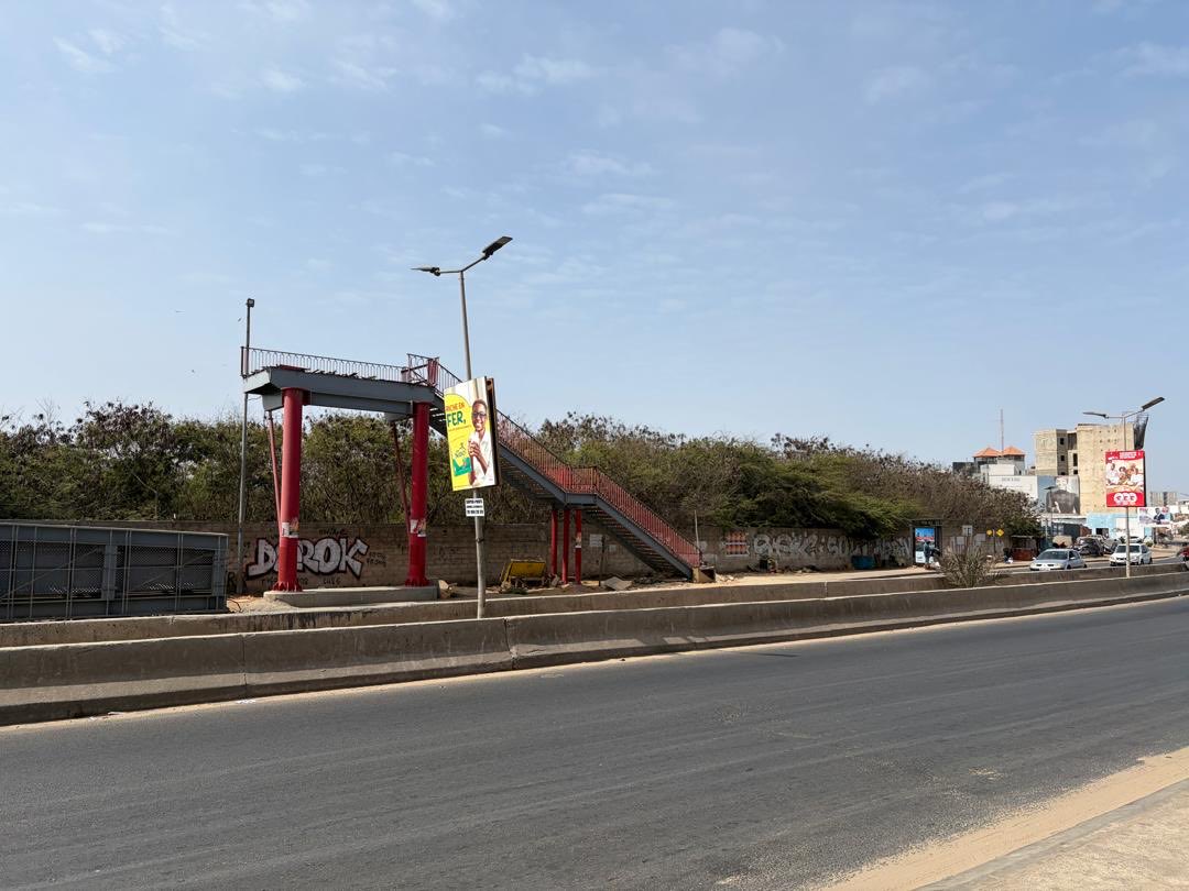 tonysue2's tweet photo. Ce pont de Tonghor Yoff arraché par un camion depuis le 11 décembre 2024 est toujours parqué sur le trottoir.  A quand sa remise en place pour permettre aux piétons d’éviter la traversée risquée de la chaussé? Ou financement perdu pour de bon? https://t.co/2uSem0UYEw