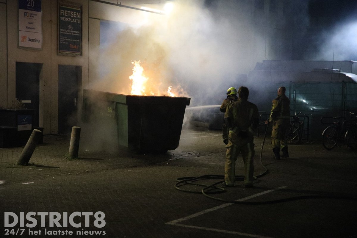 Brandweer blust containerbrand bij bedrijfspand