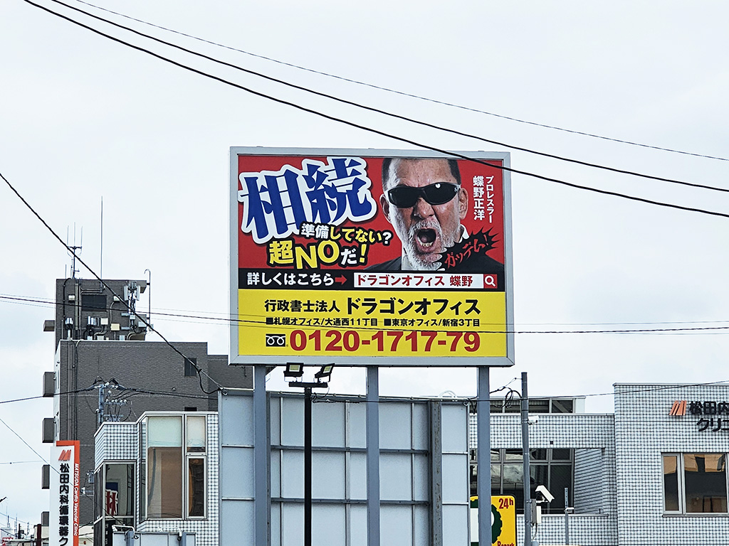 看板 行政書士法人ドラゴンオフィス』様の広告看板に蝶野正洋が起用 ・国道