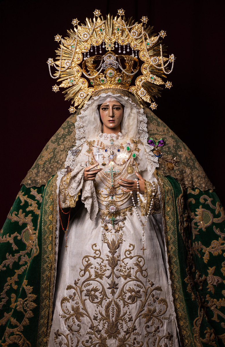 “𝐷𝑒 𝑝𝑖𝑒 𝑎 𝑡𝑢 𝑑𝑒𝑟𝑒𝑐ℎ𝑎 𝑒𝑠𝑡𝑎́ 𝑙𝑎 𝑟𝑒𝑖𝑛𝑎, 𝑒𝑛𝑗𝑜𝑦𝑎𝑑𝑎 𝑐𝑜𝑛 𝑜𝑟𝑜 𝑑𝑒 𝑂𝑓𝑖𝑟” (𝑆𝑎𝑙𝑚𝑜 45:9)

Todo guarda un significado; todo encierra un porqué. El conjunto de joyas que luce la Virgen en su atavío suponen la manifestación material del amor