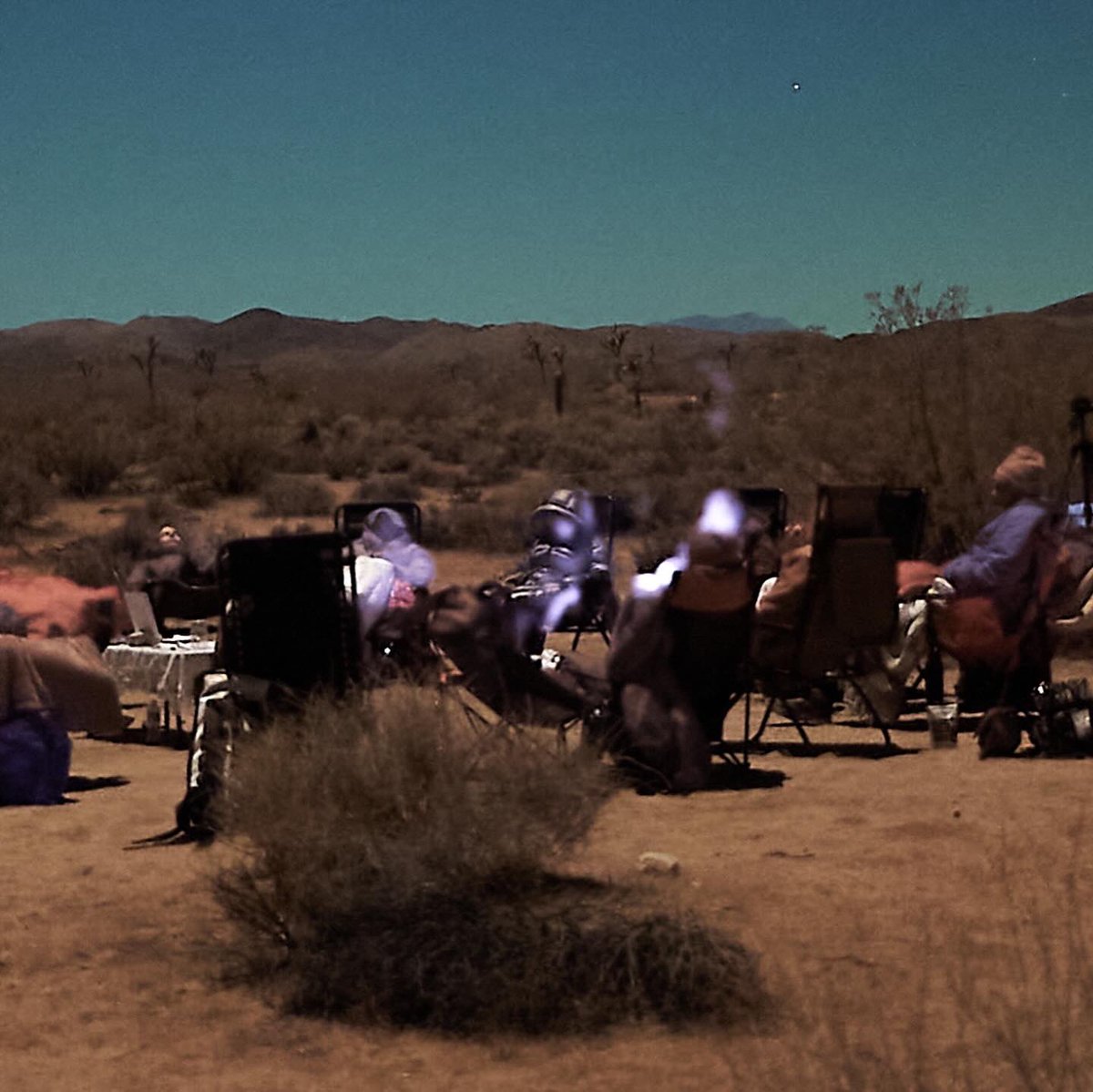 TimeCaptainFM's tweet photo. After careful review of some photos taken in a timelapse during a CE5 gathering in Joshua Tree in November, 2025, we decided this is the most unexplainable / anomalous photo. No cell phones were on. And what is that misty shape above Pat Pearsall’s head? No one’s breath was making mist, it was cold, but not that cold. This showed up in only one photo in the series, where a picture is being taken for 1/5 of a second every 5 seconds over the course of several hours. This light, or glow, showed up on three ladies as we were meditating under the stars, in the moonlight. We don’t know what the glow is. Looks pretty strange.
The other photographer there, Jeff Sell  told me he has interacted with these “Misty” beings in Joshua Tree before, he named them “Misty”. 
The last image as you swipe, at the end, are the 5 seconds before and after photos in the timelapse.