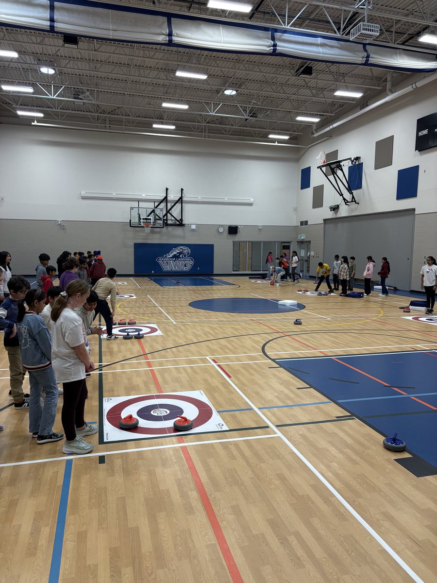 RyanPoelzer's tweet photo. Big day at @HarbourLandSch ! Trying out curling during Phys Ed. Students having a blast throwing rocks at houses! https://t.co/RTfbw9q7Wa