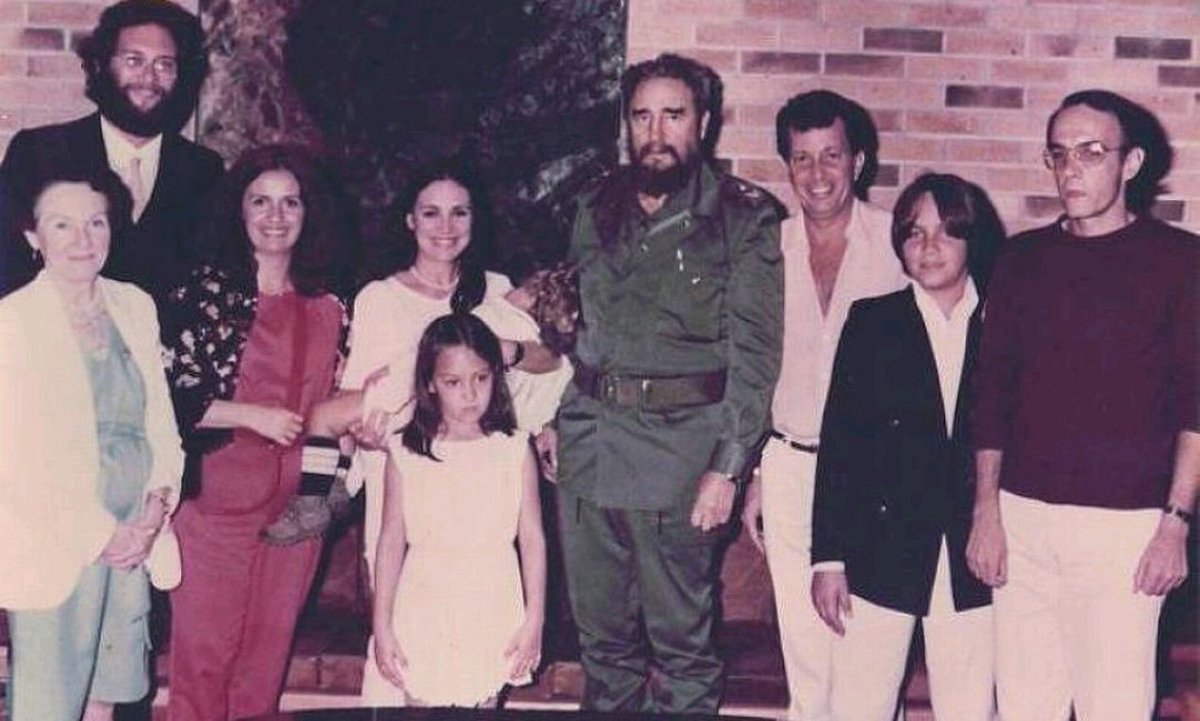 CubaOrtografia's tweet photo. No es una foto cualquiera. Es una escena cuidadosamente encajada dentro de una coreografía política donde cultura, fama y poder se dan la mano sin decirlo en voz alta. Ahí está Regina Duarte, la actriz brasileña, en la cúspide de su popularidad continental. A su lado, su hija Gabriela Duarte, todavía niña. Cerca, Daniel Filho, cerebro televisivo de una generación. Y en el centro, como eje gravitacional de todo, el esperpento de Fidel Castro.

La imagen parece doméstica. Pero no lo es. Esto no era turismo cultural. Era otra cosa.

Cuba, en los años 80, ya había perfeccionado un modelo: invitar artistas, envolverlos en reconocimiento, mostrarles una versión filtrada del país y, sobre todo, fotografiarlos en el lugar correcto, con la persona correcta. No hacía falta que dijeran nada. La imagen hablaba sola.

Un actor querido por millones, una actriz admirada en toda América Latina, entrando, aunque fuera por unos días, en la órbita simbólica del poder cubano. Eso se traducía en legitimidad, en prestigio prestado. La cultura convertida en aval político.

El guion era siempre parecido: recepción institucional, teatro lleno, intelectuales cuidadosamente seleccionados, encuentro con figuras como Nicolás Guillén y, finalmente, la foto. La foto era el clímax. No importaba si el visitante entendía el contexto completo. No importaba si cuestionaba o no. Bastaba con su presencia. Bastaba con la imagen.

Muchos artistas llegaban con curiosidad, otros con simpatía, algunos simplemente con interés profesional. Pero el sistema no necesitaba militantes. Necesitaba rostros. Porque en la lógica del poder simbólico, una figura popular vale más que un discurso ideológico. Es más digerible. Más exportable. Más eficaz.

Y ahí es donde entra el papel de la izquierda internacional: no necesariamente como conspiración organizada, sino como ecosistema que amplifica sin cuestionar. Décadas después, la foto sigue circulando. Ya sin contexto, sin matices, sin explicación.