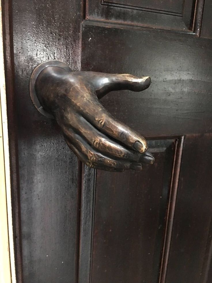 SophiaFioren's tweet image. Antique bronze doorknob designed in the shape of a realistic human hand reaching out from a dark wooden door to be shaken
