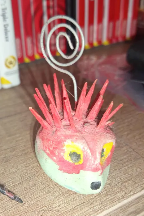 I had this thing for like... 18 years? it was made with clay, wooden sticks, and a piece of iron, it's supposed to be for hanging photos? It cost me 2€, never hung a photo on it it's dirty and the color has faded, still, I love it, It's like a red and green hedgehog, looks cool.