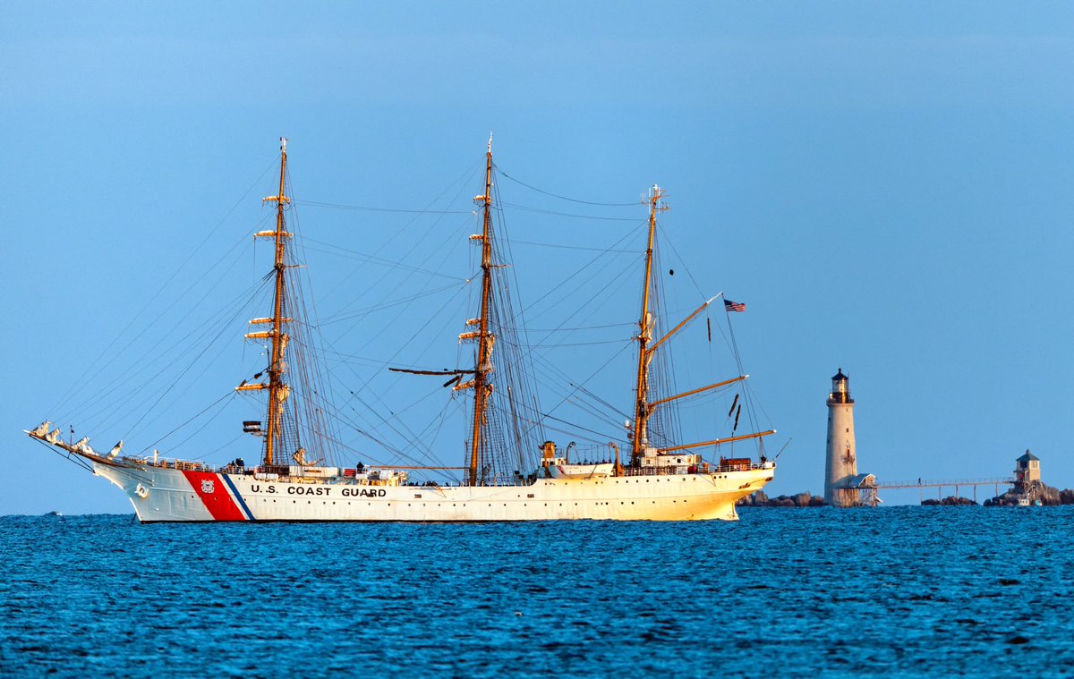 NBC10Boston's tweet photo. The United States Coast Guard Tall Ship Eagle is seen moored off Nahant shortly before sunset tonight. Graves Light is seen in the background, with what appears to be the lighthouse keeper walking the pier. 📸⁦@pictureboston⁩ https://t.co/fzYn4TUAJD