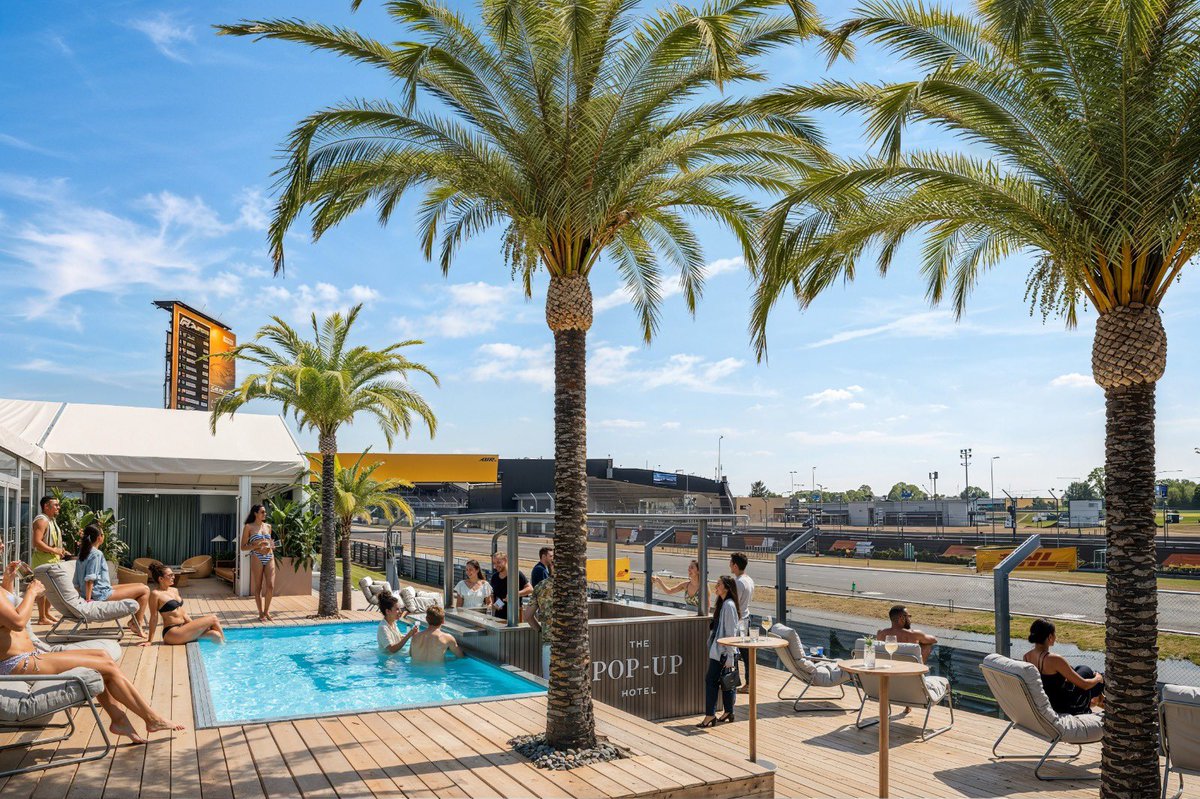 ChrisMedlandF1's tweet photo. The Pop-Up Hotel is taking a swimming pool trackside to Silverstone this year, and I can’t help feel that it’s a *very* ambitious depiction of the British summer… #F1 #BritishGP https://t.co/etX4zyjaDI