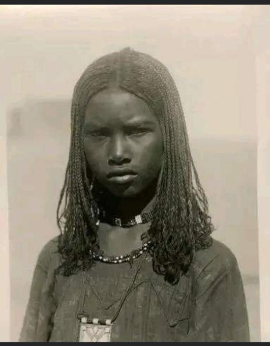 AfricanArchives's tweet image. Portrait of a bisharin girl with braided hair, beads and long tunic in Egypt, 1910.
