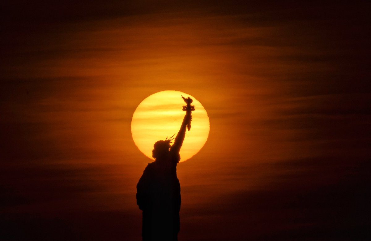 GaryHershorn's tweet photo. The sun rises behind the Statue of Liberty and the skyline of Brooklyn in New York City, Saturday morning #nyc #newyork #NewYorkCity #sunrise #statueofliberty @statueellisfdn https://t.co/28AX25fD0F