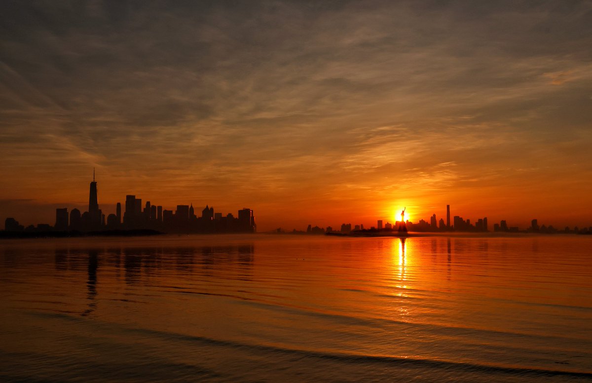 GaryHershorn's tweet photo. The sun rises behind the Statue of Liberty and the skyline of Brooklyn in New York City, Saturday morning #nyc #newyork #NewYorkCity #sunrise #statueofliberty @statueellisfdn https://t.co/28AX25fD0F