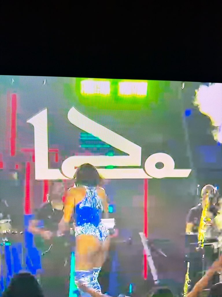 Mfelixls's tweet photo. Eu quebrando a cabeça pra entender esse símbolo no fundo do palco kkkkk. Na minha cabeça era alguém levando de frango assado 😂 fiquei me sentindo um tarado kkkk até entender que era o nome da cantora. Socorro kkkkk https://t.co/QODfnHCca5