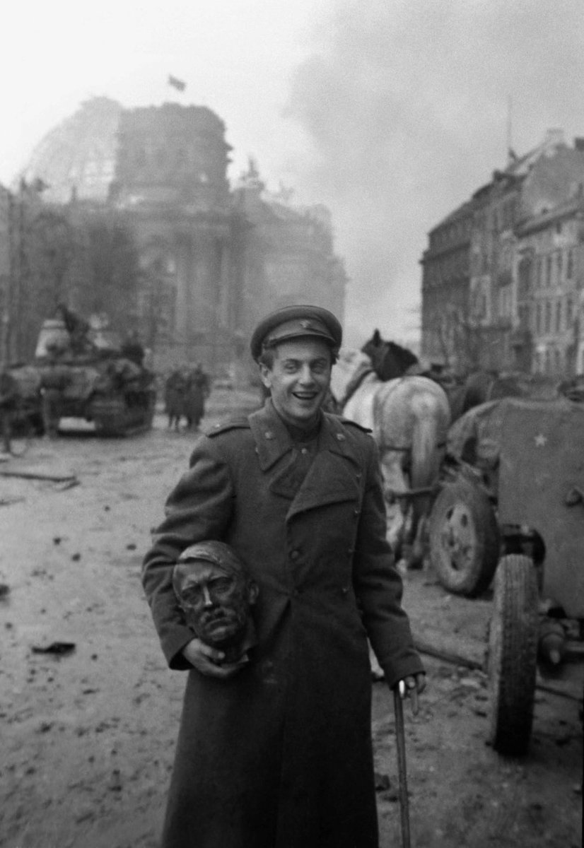 Soviet soldier carrying the head of a statue of Hitler, Berlin 1945