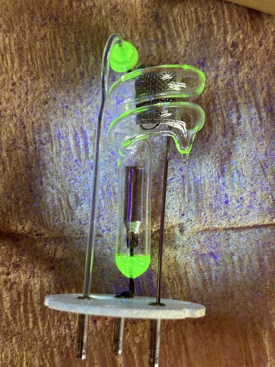 radioactivered's tweet photo. This xenon flash tube actually uses uranium glass seals and there’s a really cool engineering reason behind it. 

Uranium doped glass expands at nearly the same rate as metal when it heats up, which makes it ideal for forming strong vacuum tight seals where metal electrodes pass through the glass envelope. That matching expansion prevents stress fractures and leaks, especially in devices that experience rapid heating and cooling during operation.

Inside this tube, things can get intense so a high-voltage trigger pulse ionizes the xenon gas, turning it into a conductive plasma. Once that happens, a charged capacitor dumps its energy through the tube in a microsecond scale burst. That rapid discharge is what creates the extremely bright high intensity flash.

These types of uranium glass seals in tubes were most commonly used in the 1940s-1970s when engineers were optimizing materials for reliability in high energy vacuum devices like flash tubes and early lasers.

They’re not really used anymore, though. Modern manufacturing moved away from uranium glass mainly because of regulatory concerns around radioactive materials, even though the radiation levels are typically very low. On top of that, better alternatives were developed like using borosilicate glass, aluminosilicate glass and other types of specialized glass-to-metal sealing alloys (such as Kovar) that achieve the same or better thermal matching without the stigma or handling restrictions.

So while this green glowing uranium glass seal looks futuristic, it’s actually leftover technology from an era when engineers used radioactive materials to solve tough problems.☢️