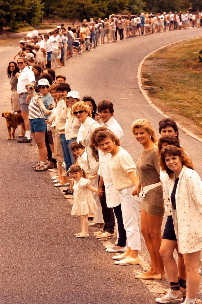 nettermike's tweet photo. Nobody thought it was possible.
But on May 25, 1986, something happened in America that has never happened anywhere in the world before or since.
At exactly 3:00 in the afternoon, five million people stepped outside — out of their homes, their routines, and their differences — and reached for the hand of a stranger.
From the southern tip of Manhattan, where a six-year-old homeless girl named Amy Sherwood started the chain, all the way to the sun-drenched shores of Long Beach, California — an unimaginable line of human beings stretched 4,125 miles across the continent. Through 16 states. Across the Mississippi River. Through the shadow of the Gateway Arch. Past the Lincoln Memorial. Right through the gates of the White House, where even the President and First Lady stepped outside to join hands.
This was Hands Across America.
It was imperfect. In the desert Southwest, the line had gaps — filled in by ribbons and ropes and sheer stubbornness. It raised $15 million for food banks and shelters, far less than the $100 million organizers had dreamed of. By every spreadsheet measure, it fell short.
But no spreadsheet could measure what really happened that day.
A farmer in Kansas stood next to a teacher from Chicago. Divers held hands underwater in Maryland. A child who had never met a celebrity found herself beside Lionel Richie. An elderly woman who had lived through the Great Depression stood tall in the sunshine and said, without words, I still believe in this country.
For fifteen minutes, ordinary people — not governments, not corporations, not algorithms — physically held this nation together.
The chain may have had gaps. But the feeling didn't.
Nearly four decades later, in a world that sometimes feels like it is coming apart at the seams, that Sunday afternoon in May still whispers something important:
We have done this before.
We reached out.
We held on.
And the hand we grabbed? It was warm.
It was real.
It was human.
We can do it again.