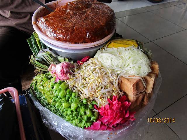 masakpartikelir's tweet photo. Jiiingaaannn, kusebut bangku keras tegak lurus dua kali, dendam itu belum tuntas rupanya kawan

Di Stasiun Cirebon, pedagang tahu gejrot naik. Tahu goreng dipotong, disiram kuah dan ulekan cabe, asam, pedas, segar, dimakan di atas nampan styrofoam kecil pakai tusuk gigi sembari kereta berhenti sebentar

Di Stasiun Purwokerto, stasiun paling lama berhenti (dan berbanding lurus dengan pedagang asongan yg masuk), apapun dijual, sambil berakrobat supaya tidak menginjak penumpang (yg tidur di tengah gerbong). 

Mendoan tempe tipis dibalut tepung basah, digoreng setengah matang, masih lemas, masih panas. Lanting, kudapan bulat dari singkong khas Banyumas, keras, gurih, bolehlah dikunyah sepanjang perjalanan

Lalu pedagang pecel datang. Ada sesuatu berwarna pink segar dengan aroma tajam yg unik dan semerbak. Aku tau namanya sekarang: Kecombrang, dicampur sayur rebus dan bumbu kacang, disajikan di pincuk daun pisang

Gongnya, kalau sudah mendekati Purworejo, ada dua penanda yang hampir selalu datang bersamaan, pedagang dawet ireng naik, minuman hitam dari tepung beras dan gula aren yang warnanya gelap, tampilan boleh sederhana tapi nikmat ketika menyentuh tenggorokan, yang kedua adalah yang paling kutakuti, banci ngamen, aku takut digoda dan tergoda (guyon suuu)