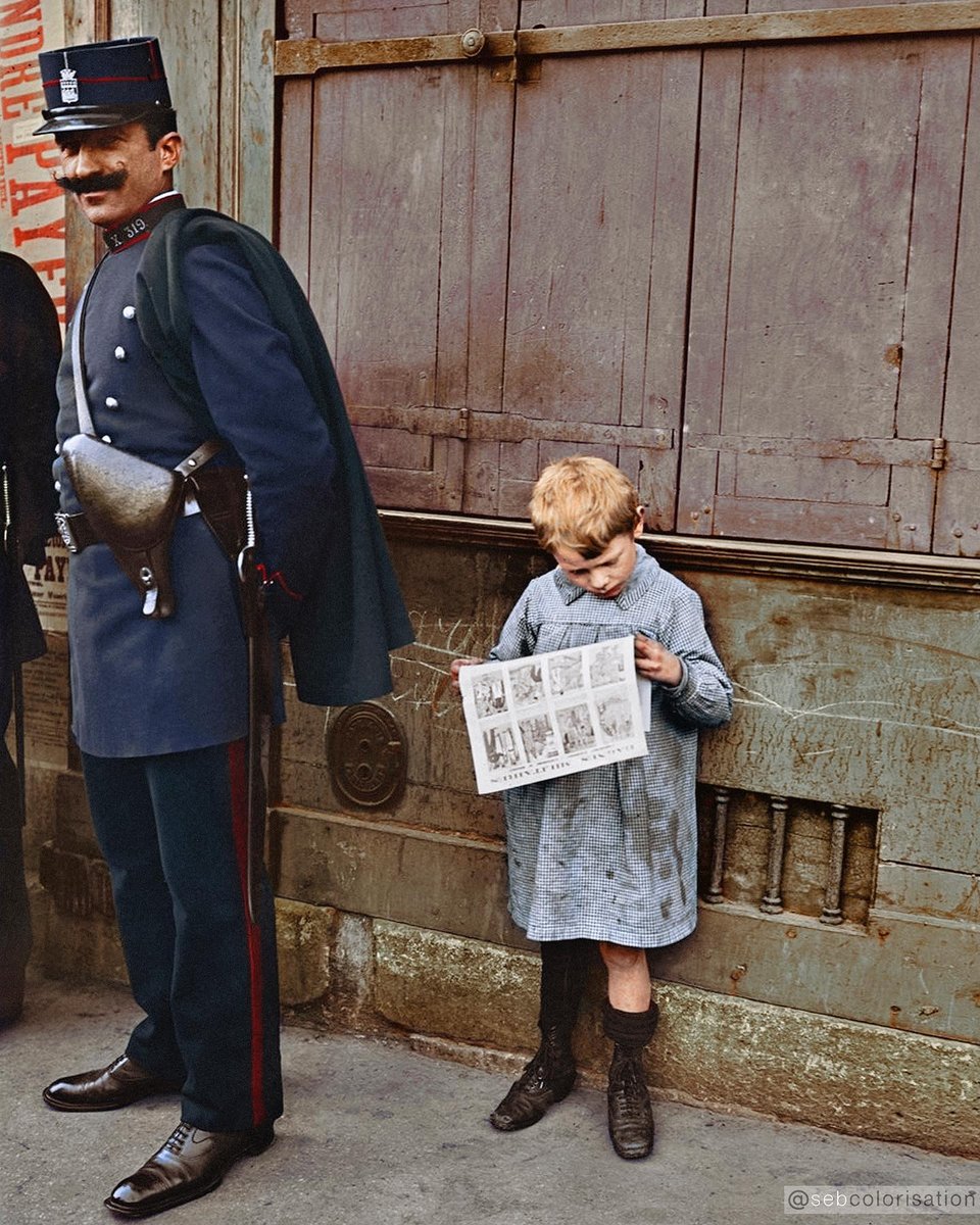 A child reads a newspaper beside a police officer in Paris, France, on May 1, 1912. Colorized by sebcolorisation on Instagram.