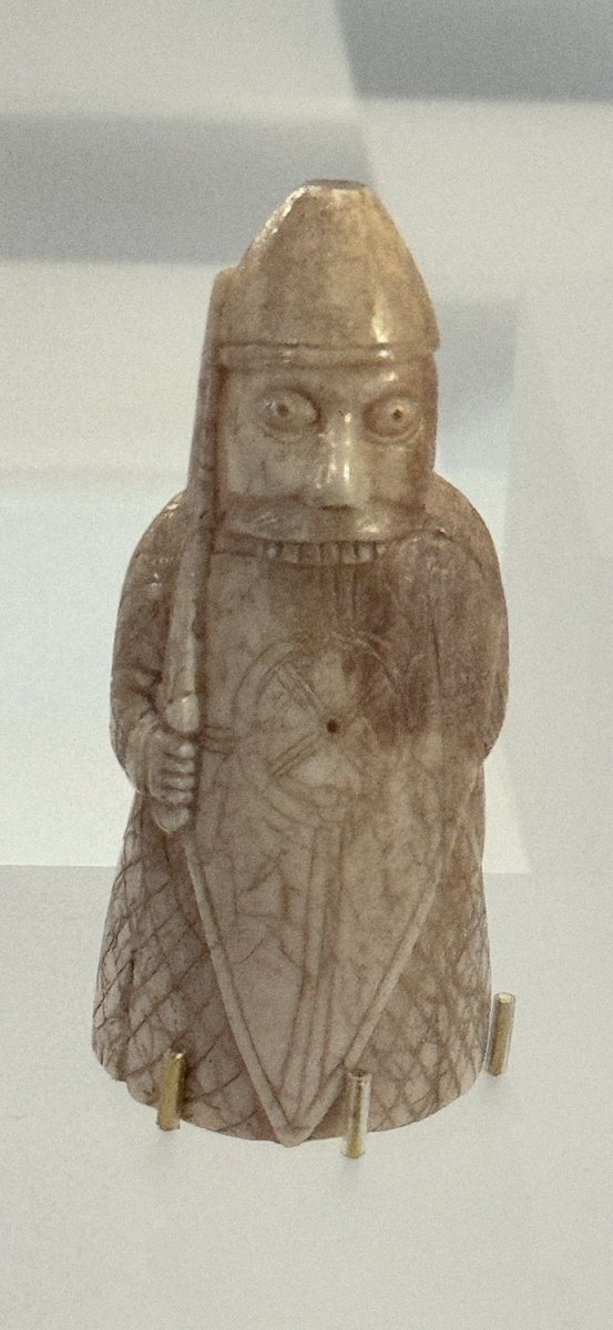 Dunringle's tweet photo. Lewis Chessmen ‘Berserker’ in Museum Nan Eilean. This is 1 of the chessmen on an exchange visit whilst the usual ones are getting an overhaul. 
Note the wind-turbine on his shield!  
The Lewis Chessmen-supporting green energy since the period 790CE to 1266CE &amp; present day. https://t.co/w0RVwIKk06