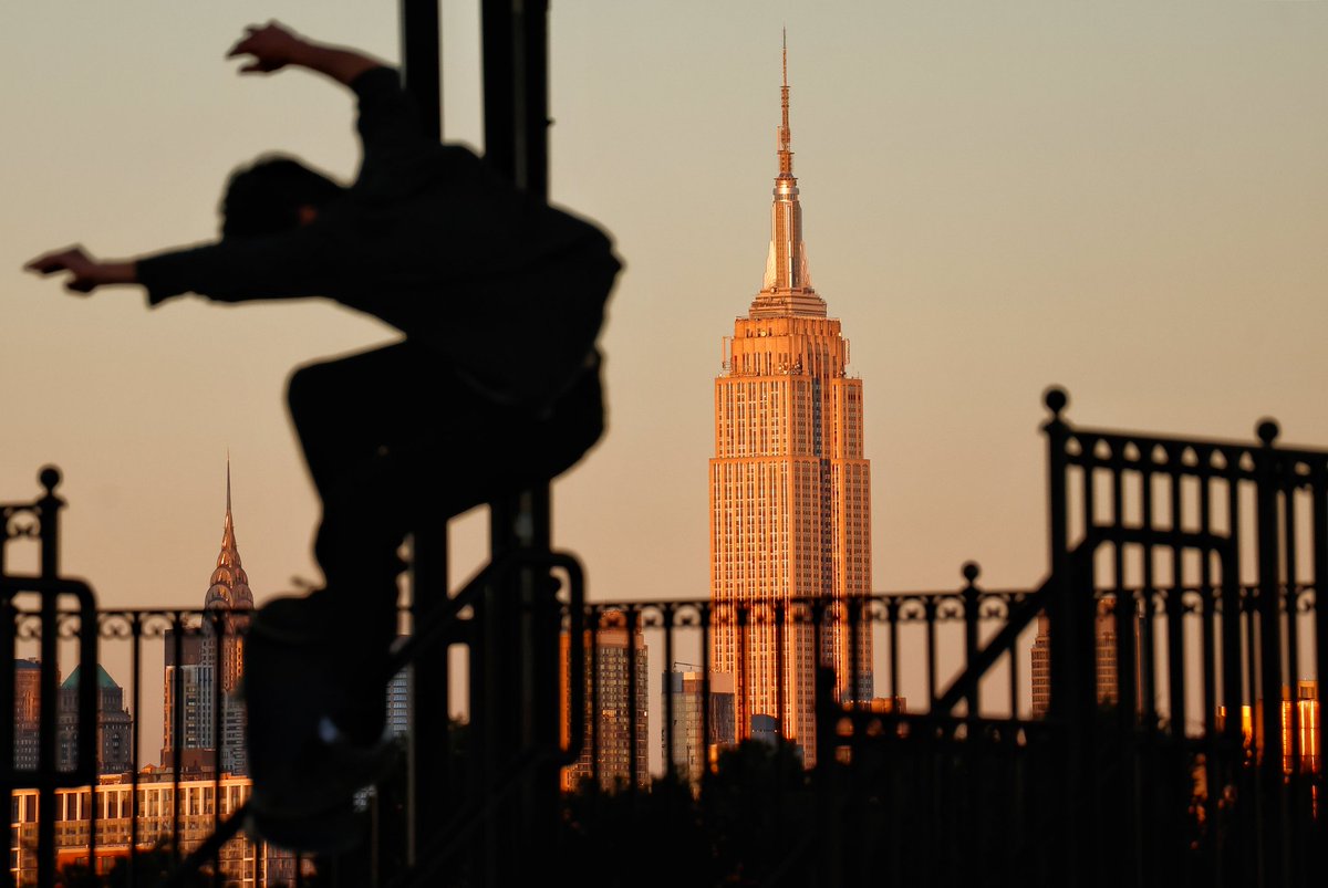 GaryHershorn's tweet image. People in a park in the Jersey City Heights dancing, skateboarding and walking in front of the Empire State Building in New York City as the sun sets, Saturday evening #newyorkcity #nyc #newyork @empirestatebldg #jerseycity