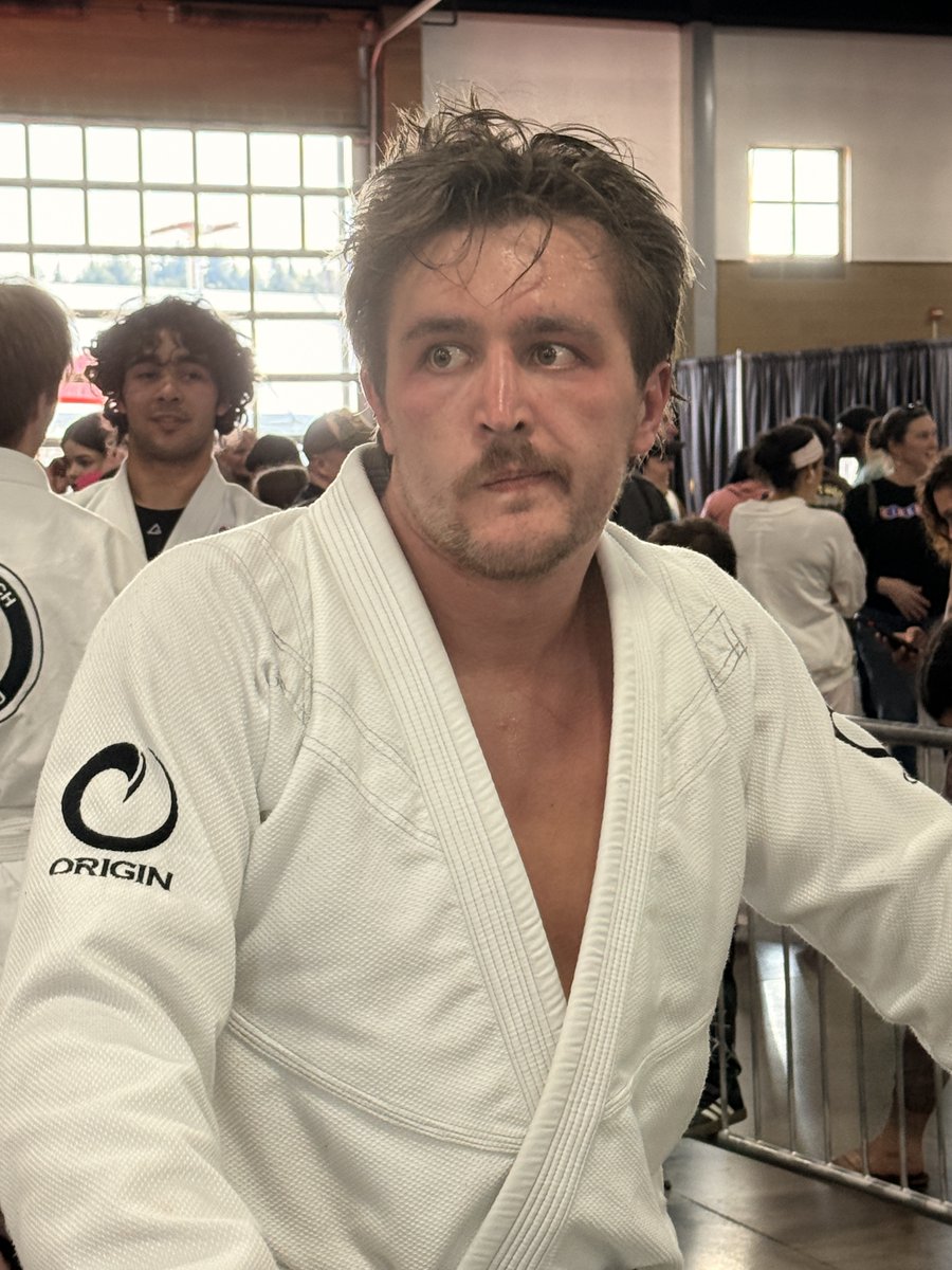 davepl1968's tweet photo. This is my son, of whom I’m incredibly proud, after losing a tournament. 

He took up TKD as a kid, went to state in wrestling in high school, and just recently decided to give Jiu-Jitsu a try as an adult.  This was his first tournament. And with 1200 or so competitors total, he earned silver. And yes, of course, I have a smiling podium photo, but while he may not agree, I like this crooked candid one a lot better.

It’s right after his loss in the final round, as he contemplates what just happened. He’s stewing about it, you can tell. Now he knows something he didn’t know five minutes ago: that the arm bars in the gym are done respectfully, but in tournaments, they need to be done more forcefully. And now he’s wishing he knew that five minutes ago.

But he’ll know it next time – and then inevitably run into the next thing he didn’t know. Repeat and rinse. It’s how we learn and grow… if we do. It’s the whole point.

Always aim for gold in all the things you do, but if the thing you’re doing isn’t “your main thing”, always be ready to be well pleased with silver. Just remember that thinking about it on the sofa is not the bronze.

As for me, I’m not and have never been a “sports dad”.  I’m just proud he trained and showed up! 

I mean, I’m 6'2" and built like a linebacker, but I’ve got dyspraxia from autism, so suffice it to say my role on the high school football team was "AV guy".  And so my kids’ athletic achievements are generally like art or wizardry to me, not something I can vicariously participate in through them. Which has made all the difference, I think… zero pressure, maximum pride.