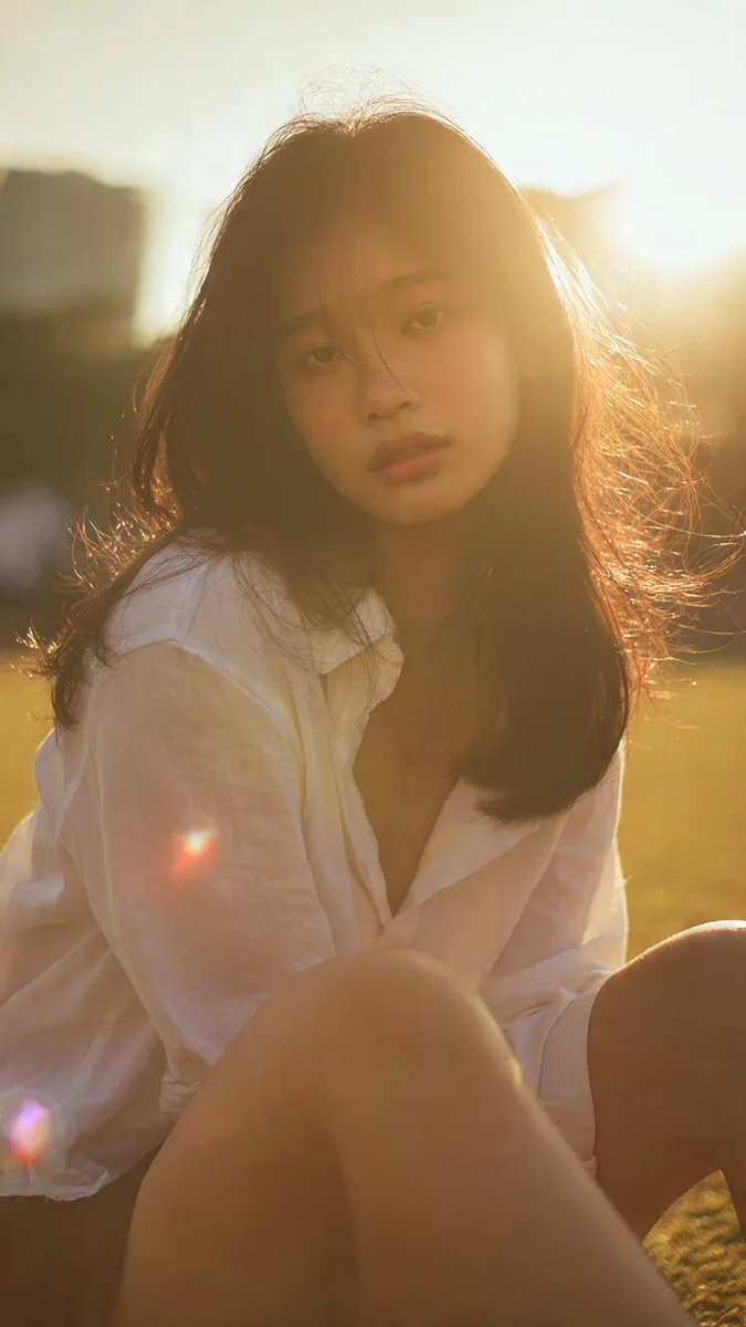 Ciri_ai's tweet image. Gemini Nano Banana Pro 

Prompt: Cinematic portrait of a young asian woman sitting on grass outdoors, soft direct gaze to camera, natural pose with slightly leaning forward posture, wearing a loose white shirt, dark skirt, gentle wind moving her hair, minimal background with soft