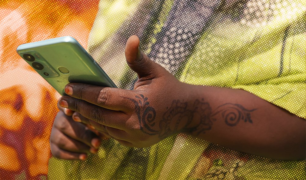 Person holding a mobile phone in a refugee camp setting, representing access to support services through voice technology.