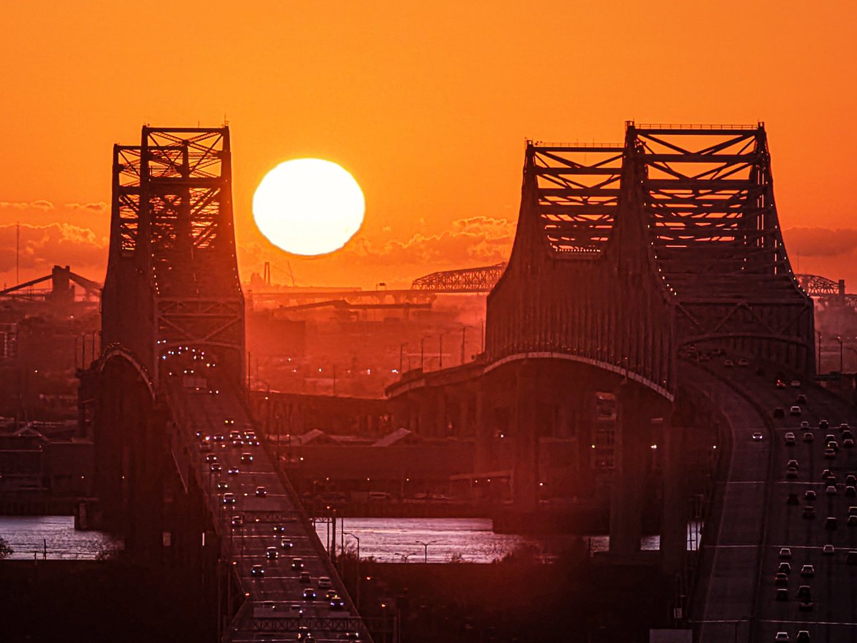 The sun sets between the Crescent City Connection bridges, New Orleans