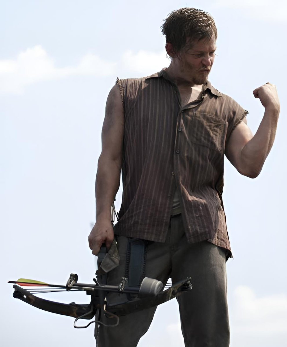"Norman Reedus flexing that arm while holding his crossbow… I’m not okay   Sleeveless ripped shirt clinging to his sweaty chest, bicep popping, veins showing, messy hair, that intense focused stare…  He’s standing there looking like pure rugged masculinity and danger. The way