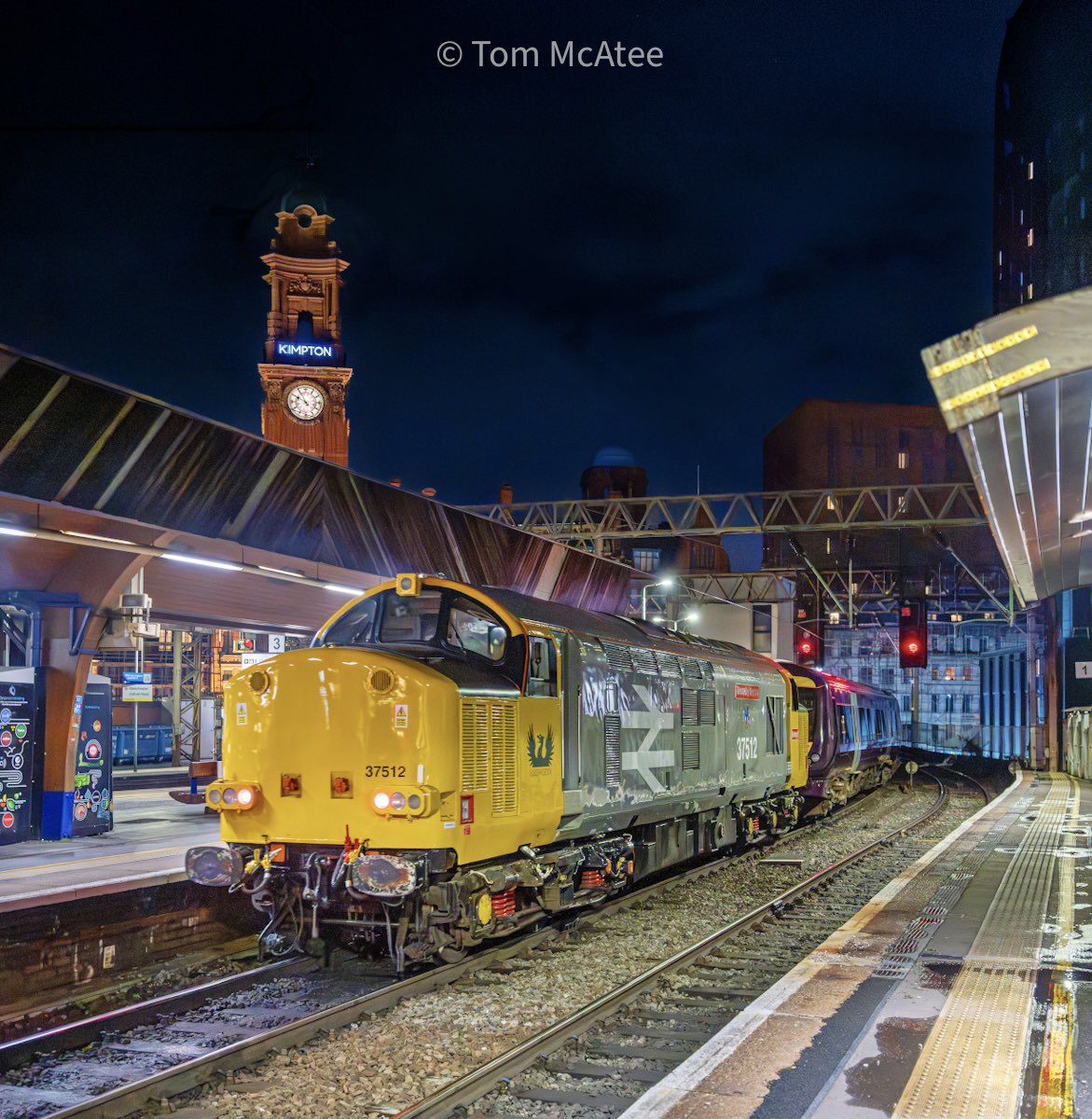 McateeTom's tweet image. Looking very smart in Railfreight livery, 37512 'Thornaby Demon' poses under Man Oxford Road’s Kimpton Tower Clock Hotel with the 5Z14 19:23 Warrington to Derby EMR Class 170 drag 📸 🏙️

⭐️ Gift Store ⬇️🏞️🚂
railwayartprintshop.etsy.com

#class37 #railfreight #freightfriday #railways