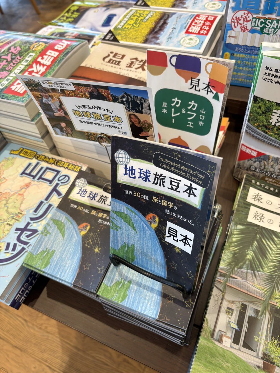 mamehon2021's tweet photo. 最新刊の「＃地球旅豆本」が〝母港〟の一つ、山口県周南市の「＃蔦屋書店周南市立徳山駅前図書館」に着いた。6年前にこの街で生まれた豆本は8作目。海外留学を経験した山口大学の学生有志￼が新たな気づきを記事に込めた。
いつも一等棚をありがとうございます。
写真撮影は桑田昭ニ氏
@townreporter https://t.co/VN1wAtGaDe