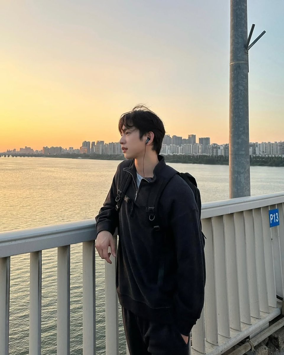 The bridge stretches beneath my feet like a fragile line between who I was and who I am becoming, while the sunset spills across the sky in soft fire, whispering that even the day knows how to let go without losing its beauty.