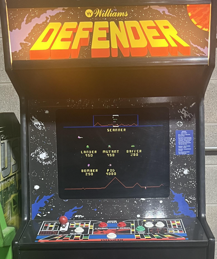 Defender (1981). The logo is a custom typeface, with Countdown used for the text on the controls.

The game is very difficult to play at first: a side-scroller where you can reverse direction and jump to hyperspace, you have 5 buttons for thrust, weapons and direction, plus a