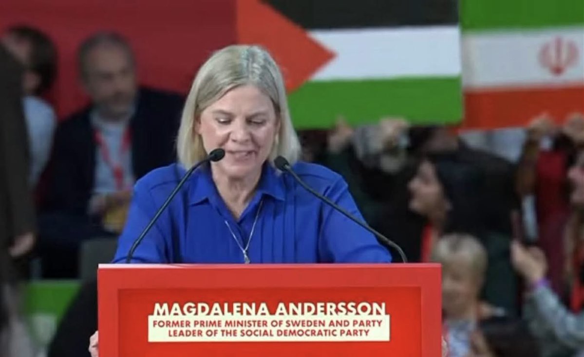 Magdalena Andersson håller tal under flaggorna av Hamas och den iranska regimen. Global socialism är ondska.