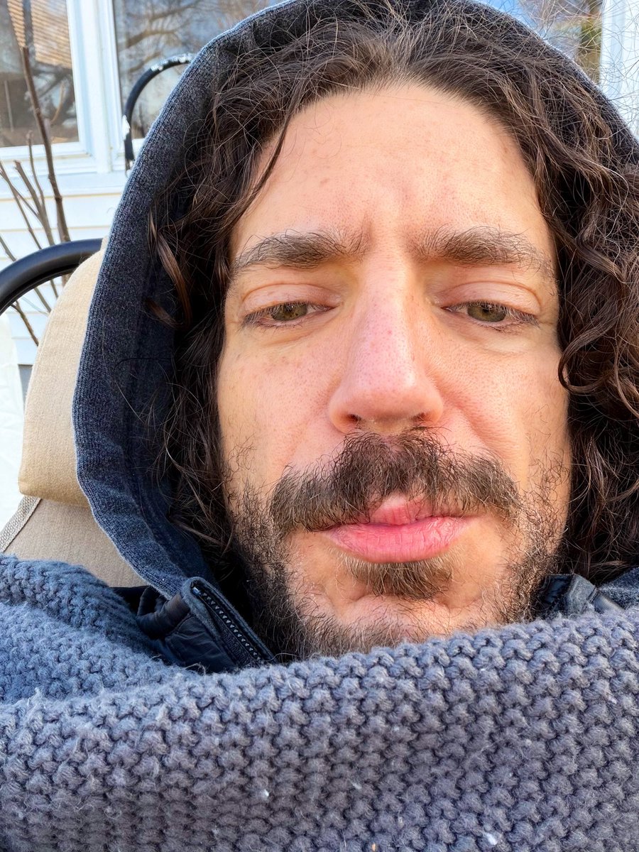image description: man with unkempt facial hair and frizzy hair celebrates the holiday under a blanket in his backyard 🤙🏼